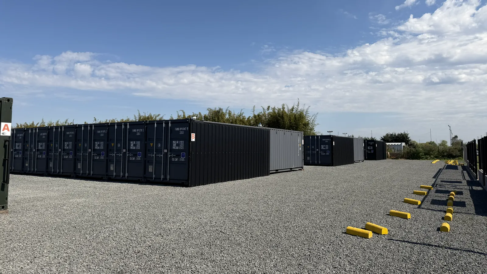 Explanada de grava con containers negros y topes de estacionamiento amarillos en el predio de Zpacio Storage